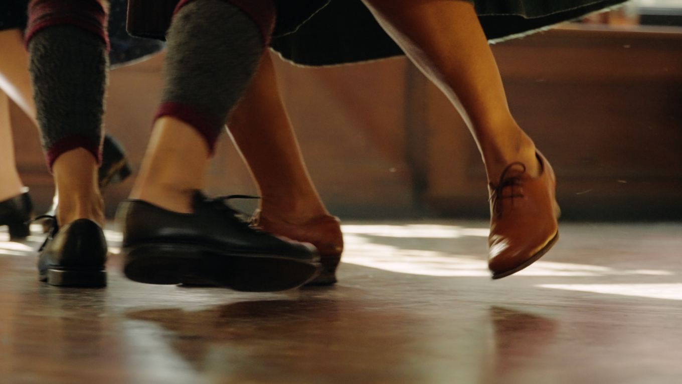 Zwei paar Füße, die miteinander tanzen in Trachtenschuhen.