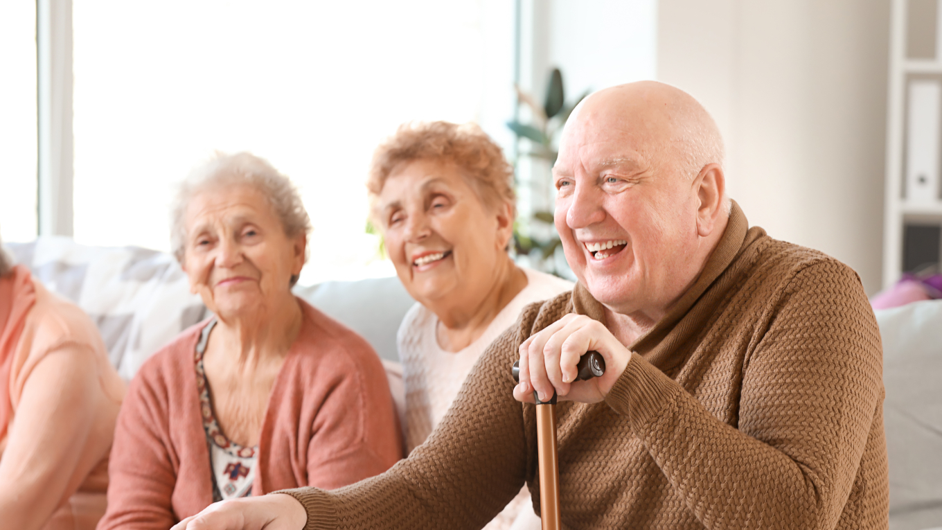 drei ältere Menschen sitzen nebeneinander und lachen