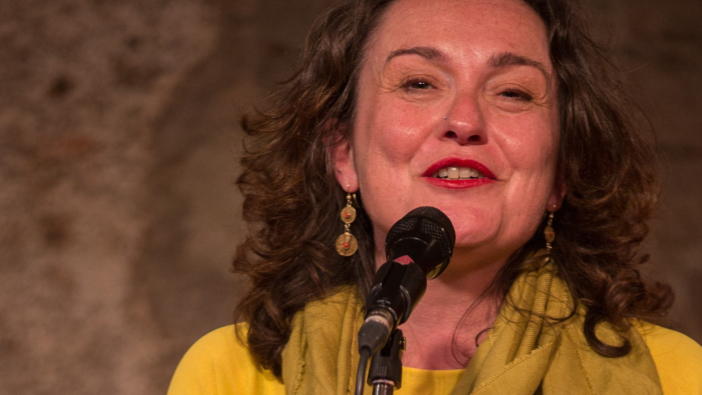 Eine Frau im gelben Kleid singt vor einem Mikrofon
