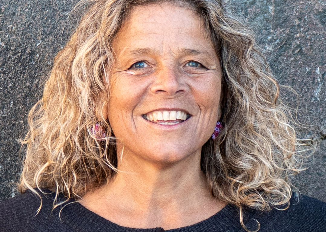 Eine Frau mit blonden langen Locken lächelt in die Kamera