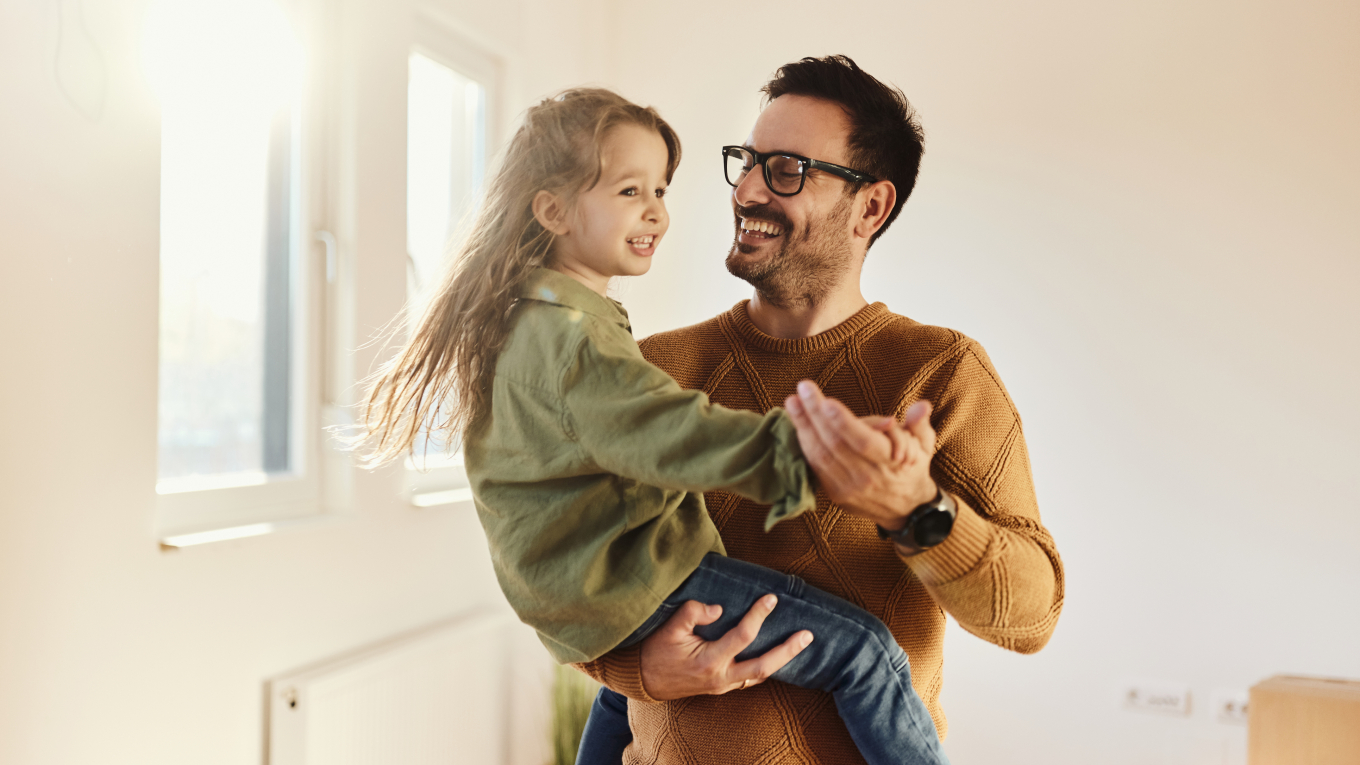 Glücklicher alleinerziehender Vater hat nach dem Umzug in eine neue Wohnung Spaß beim Tanzen mit seiner kleinen Tochter.