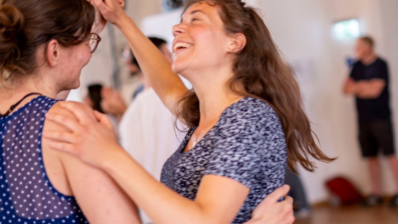 Zwei Frauen tanzen miteinander und lachen