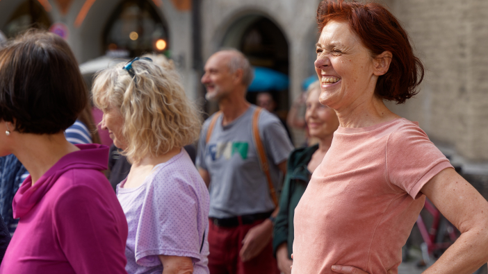 mehrere Menschen nach links gewendet folgen einem Jodelvermittler